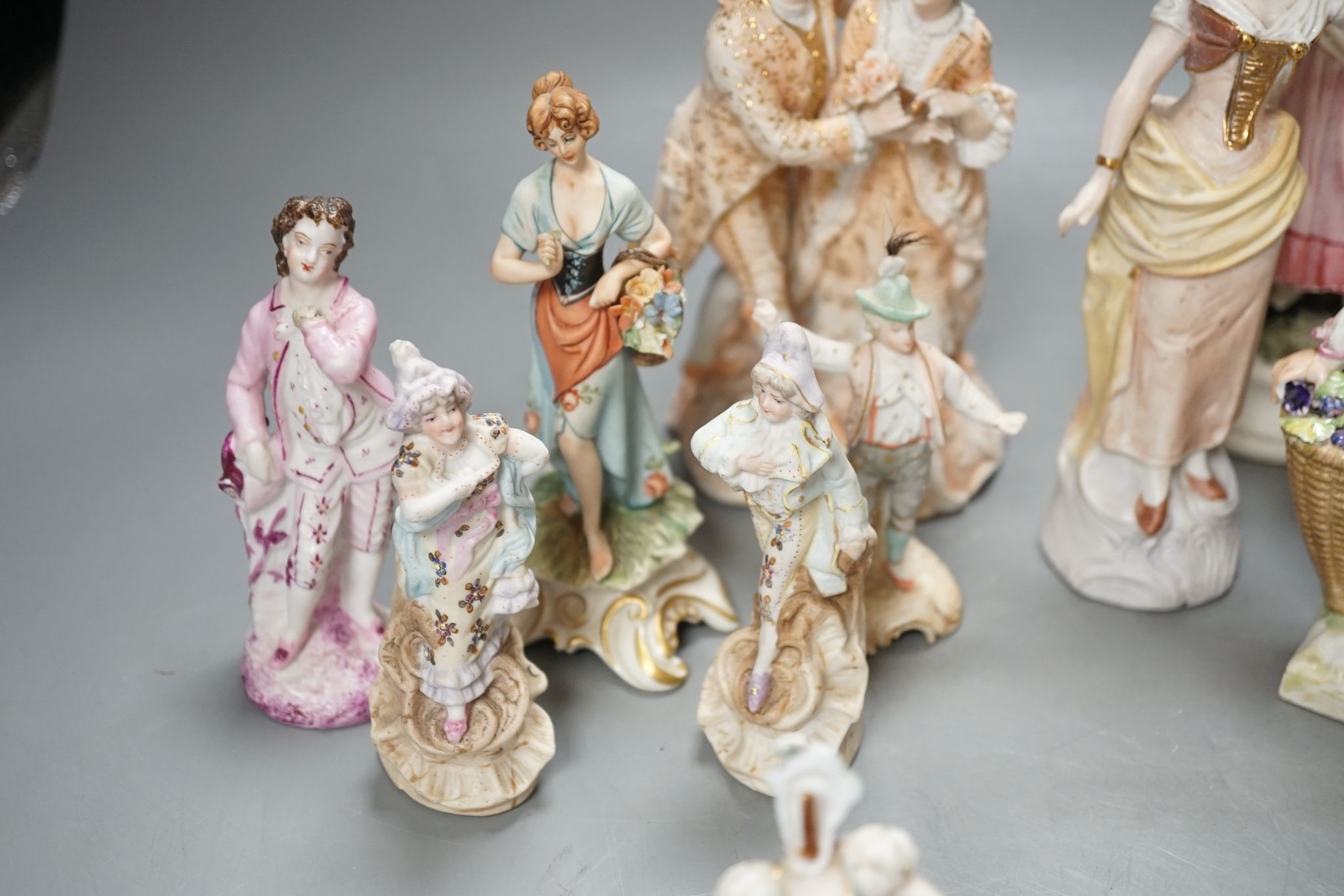 Ten French bisque figures and a Berlin figure of a grape picker, tallest 19cms high.